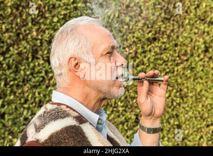 Portrait de l'homme âgé adulte qui fume une cigarette électronique. Banque D'Images