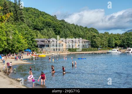 Personnes sur la plage à Luss à côté du Loch Lomond.Avec Lodge sur Loch Lomond hôtel en arrière-plan. Banque D'Images