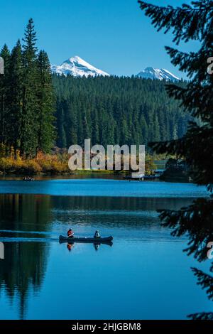 Canoë sur l'eau froide et claire du lac Clear du centre de l'Oregon avec les trois Sœurs en arrière-plan. Banque D'Images