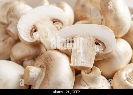 Champignon cru et champignons de Paris entiers coupés en deux.Fond de champignons blancs cultivés.Gros plan sur Agaricus bisporus.Protéines végétales.Régime. Banque D'Images