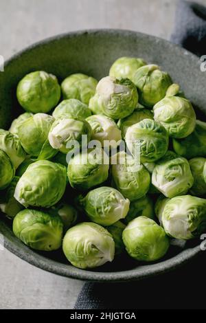 Tas de choux de bruxelles bio crus pelés mini chou dans un bol en céramique sur fond gris clair.Légumes saine alimentation. Banque D'Images