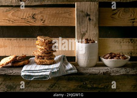 En-cas maison sucrés.Bol de noix d'amande grillées au miel glacé et pile de biscuits de sucre sablé carrés sur une ancienne étagère en bois.Style rustique, classi Banque D'Images
