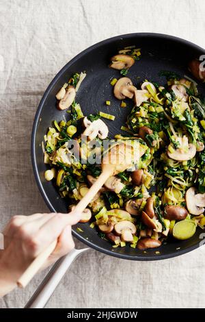 Faire sauter les champignons, les poireaux et les épinards dans une casserole Banque D'Images