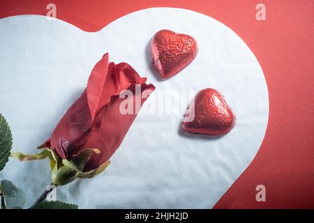 Helsinki / Finlande - 29 JANVIER 2022 : gros plan des confiseries au chocolat en forme de coeur, et des roses rouges sur fond rouge vif. Banque D'Images