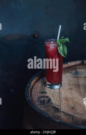 Boisson au basilic de fraise dans le grand verre Collins avec paille à boire de papier sur le fût en bois Banque D'Images