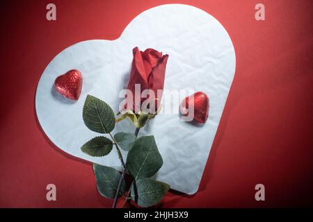 Helsinki / Finlande - 29 JANVIER 2022 : gros plan des confiseries au chocolat en forme de coeur, et des roses rouges sur fond rouge vif. Banque D'Images