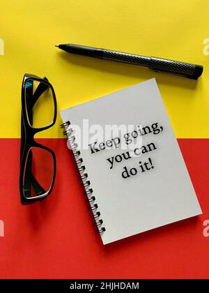 Concept motivant et motivant - continuez, vous pouvez le faire.Avec lunettes, stylo, fond jaune et rouge.Concept de motivation. Banque D'Images