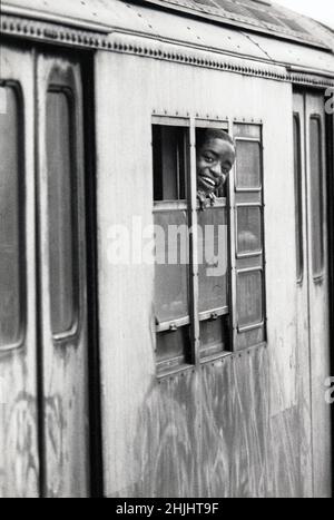 Un jeune lad souriant par la fenêtre d'une voiture de métro D train.Sur un métro surélevé à Brooklyn, New York vers 1976. Banque D'Images