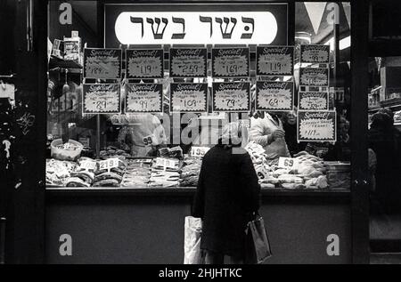 Photos du milieu des années 1970 d'une femme juive faisant du shopping dans une boucherie casher sur Brighton Beach avenue à Brighton Beach, Brooklyn, New York. Le signe hébreu dit viande de casher. Banque D'Images