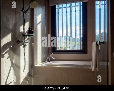 Dans la salle de bains avec la lumière du soleil à la sale fenêtre en verre de tache de l'extérieur.Salle de bains avec cloison en verre, douche, et une serviette blanche propre pour le TH Banque D'Images