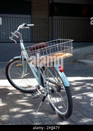 Vue arrière de vélo bleu vintage avec panier en acier garé près du bâtiment de l'hôtel, service pour les clients, client du complexe, style vertical. Banque D'Images
