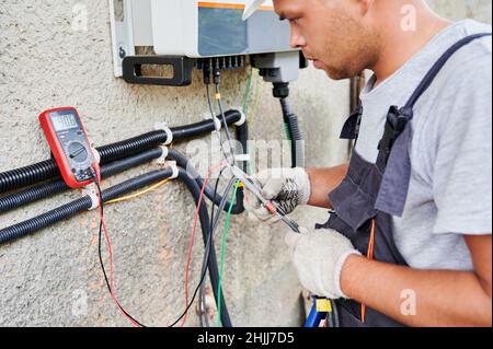 Homme électricien installant le système de panneau solaire.Un technicien en gros plan doit porter des gants pour fabriquer l'onduleur et le boîtier électrique.Concept d'énergie alternative et renouvelable. Banque D'Images