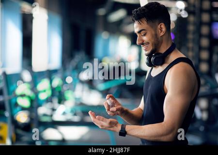 Sportif Arab homme appliquant du désinfectant vaporisez sur les mains avant de vous entraîner à la salle de sport Banque D'Images