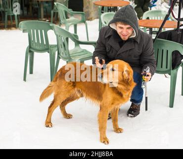 Un blogueur de sexe masculin filait avec son chien pour un blog en plein air en hiver.Concept de blogging de voyage et propriétaire d'animal de compagnie Banque D'Images