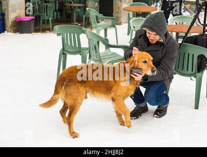 Un blogueur de sexe masculin filait avec son chien pour un blog en plein air en hiver.Concept de blogging de voyage et propriétaire d'animal de compagnie Banque D'Images