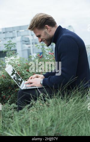 homme travaillant sur un ordinateur portable dans le parc, en déplacement professionnel, en train d'apprendre et de travailler à distance, indépendant Banque D'Images