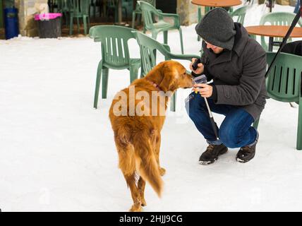 Un blogueur de sexe masculin filait avec son chien pour un blog en plein air en hiver.Concept de blogging de voyage et propriétaire d'animal de compagnie Banque D'Images