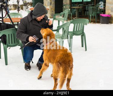 Un blogueur de sexe masculin filait avec son chien pour un blog en plein air en hiver.Concept de blogging de voyage et propriétaire d'animal de compagnie Banque D'Images