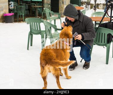 Un blogueur de sexe masculin filait avec son chien pour un blog en plein air en hiver.Concept de blogging de voyage et propriétaire d'animal de compagnie Banque D'Images