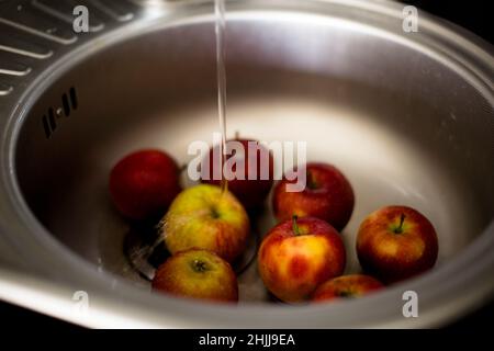 les pommes sont lavées dans un évier sous un robinet sous l'eau courante Banque D'Images