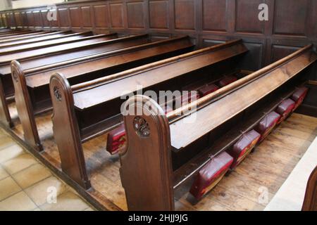 Rangées de ragoûts en bois de l'église avec coussins à genoux. Banque D'Images