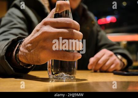 Un verre de bouteille d'eau, une bouteille d'eau accrochée par une main d'homme.Photo sélective à l'intérieur d'un café Banque D'Images