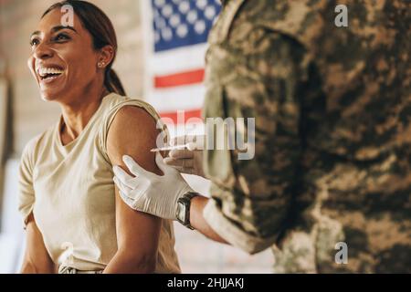 La militaire américaine reçoit une dose du vaccin Covid-19 dans l'hôpital militaire.Une femme joyeuse riant avec joie tout en s'injectant Banque D'Images