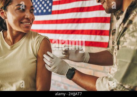 Un servicewoman souriant se fait vacciner pendant la pandémie du coronavirus.Un soldat des États-Unis a reçu un vaccin Covid-19 tiré d'un physi militaire Banque D'Images