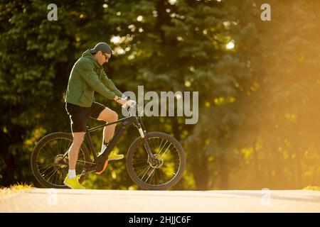 Beau jeune homme à vélo électrique dans la nature Banque D'Images