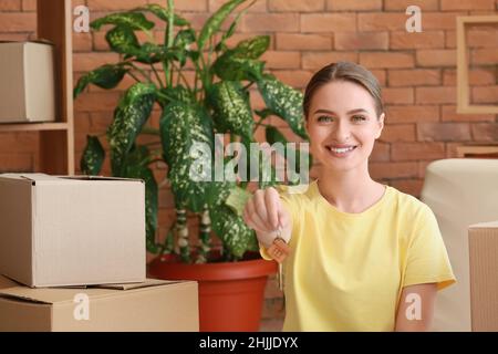 Bonne jeune femme avec clé dans son nouvel appartement Banque D'Images