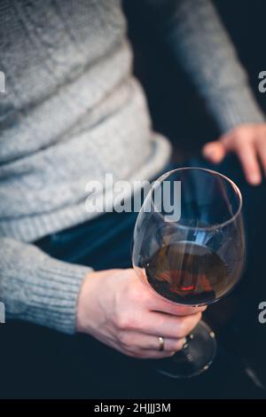 Décontracté, serein, riche, solitaire, d'âge moyen, un homme seul boit du vin rouge, se détendant sur un canapé à la maison, se reposant sur un canapé tenant une dégustation de verre Banque D'Images