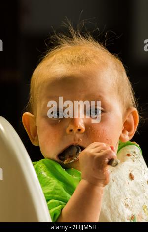 Un portrait d'un bébé qui apprend à manger. Banque D'Images