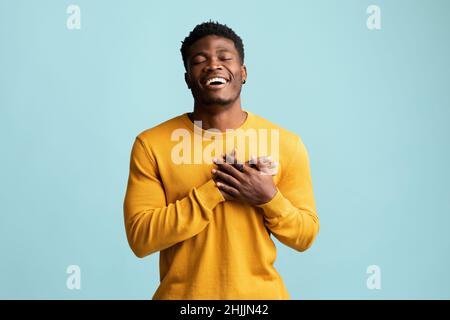 Religieux jeune homme noir priant sur bleu Banque D'Images