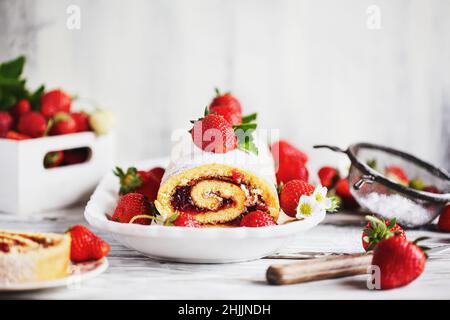 Roulades à gâteau sablé faits maison aux fraises ou roulade avec confiture de baies et sucre en poudre avec feuilles de menthe. Banque D'Images