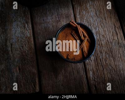 poudre de cannelle et bâtonnets dans un bol sur une table rustique en bois Banque D'Images