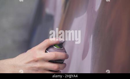 Une main avec un vaporisateur qui dessine un nouveau graffiti sur le mur. Photo de l'élaboration d'un graffiti sur un mur en bois close-up. Le concept de st Banque D'Images