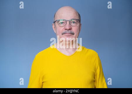 Homme hispanique senior essayant ses nouvelles lunettes.Studio tourné sur fond bleu Banque D'Images