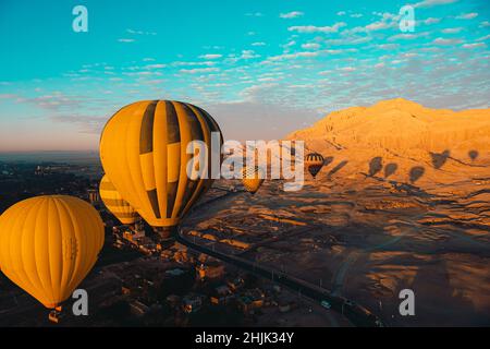 Plusieurs ballons d'air chaud jaune et orange à louxor egypte, pendant le décollage tôt à basse hauteur.Incroyable zone de sable dans la distance pendant le lever du soleil, brig Banque D'Images