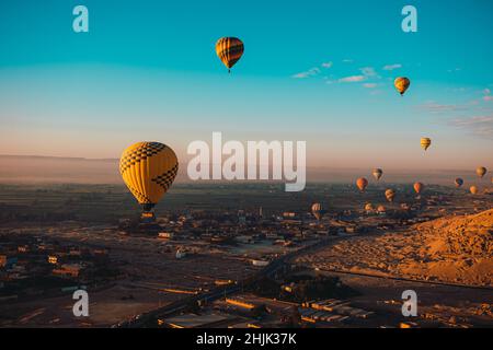 Photo verticale incroyable de dizaines de ballons d'air chaud volant autour de la région de louxor egypte.La zone orange du désert tôt le matin.Ciel bleu vif Banque D'Images