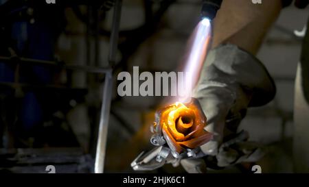 Le forgeron aligne les feuilles de rose de fer et fait la forme finale de la fleur.Forgeron fait une rose de fer. Banque D'Images