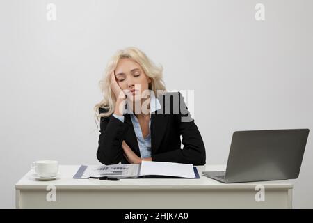 Jeune femme d'affaires fatiguée dormant sur son bureau devant un ordinateur portable, travaillant trop, se sentant épuisée au bureau Banque D'Images