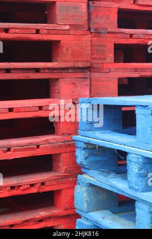 Palettes en bois bleu et rouge empilées les unes à côté des autres donnant une image abstraite et une texture contrat de couleur Banque D'Images