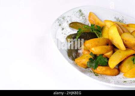 Tranches de pommes de terre frites sur une plaque blanche marinées au concombre, isolées sur fond blanc. Banque D'Images