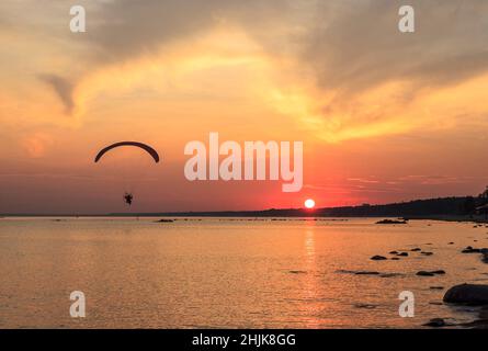 Coucher de soleil sur la mer.Réflexion du soleil dans l'eau.Silhouette de parapente volant dans le ciel.Coucher de soleil sur la plage en été.Golfe de Finlande, Ba Banque D'Images