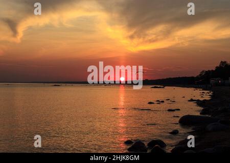 Coucher de soleil sur la mer.Réflexion du soleil dans l'eau.Silhouette de parapente volant dans le ciel.Coucher de soleil sur la plage en été.Golfe de Finlande, Ba Banque D'Images