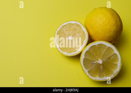 deux demi-citrons et un citron entier sur fond de papier jaune clair avec beaucoup de place pour le texte Banque D'Images