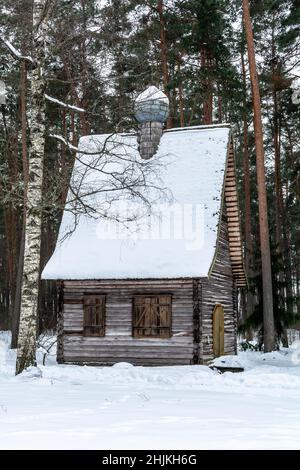 Ancienne église orthodoxe en bois de rondins couverte de neige dans une forêt d'hiver. Banque D'Images