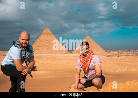 Deux hommes voyageurs posant devant les grandes pyramides de gizeh au caire égypte.Voyager en égypte pendant l'hiver, hiver froid jour couvert. Banque D'Images
