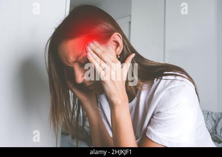 Jeune femme touchant ses temples et souffrant de douleurs à la tête, de maux de tête ou de migraine Banque D'Images