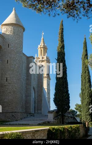 Vue verticale des tours de l'église Santa Maria la Mayor à Esteba (Espagne) parmi les cyprès, le matin d'hiver ensoleillé Banque D'Images